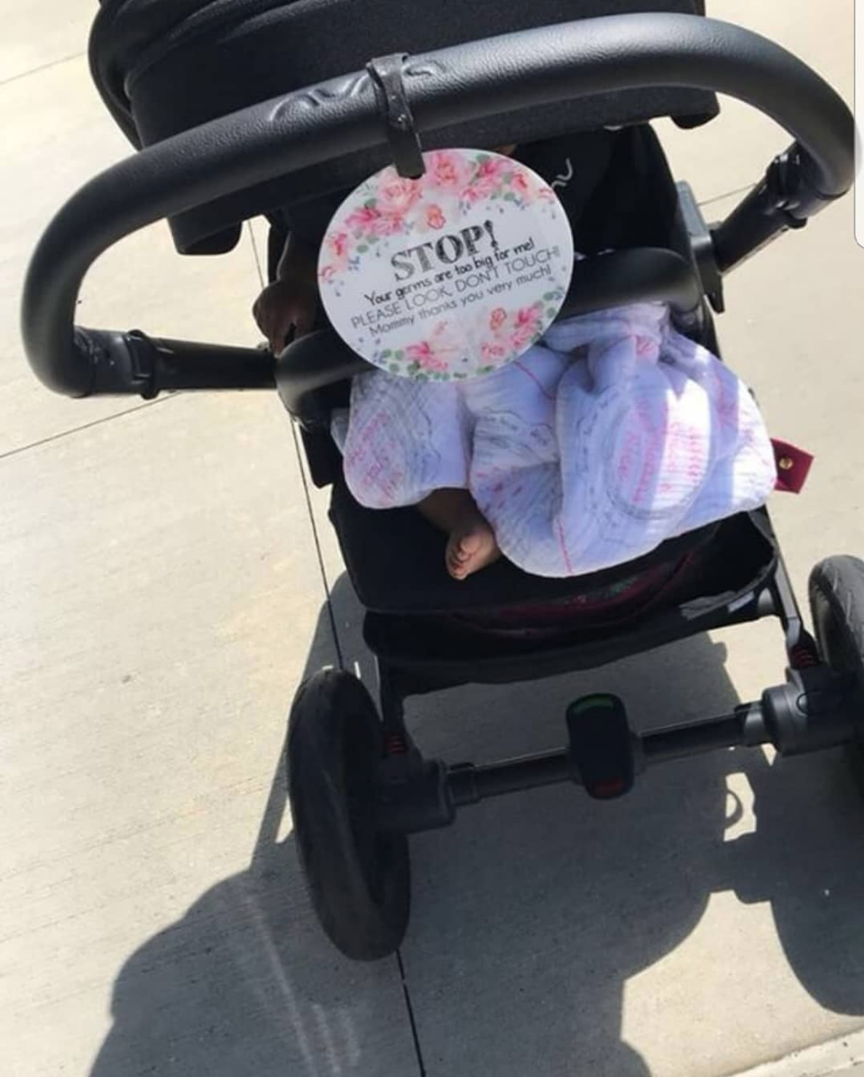 Little newborn girl in her car seat with a stop no touching baby sign perfect preemie gift