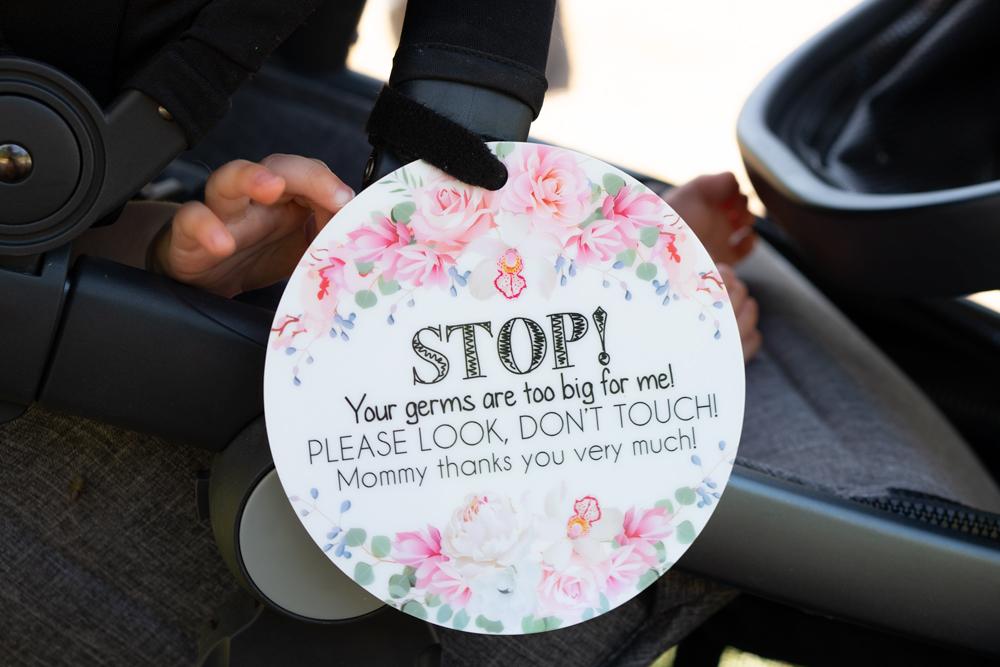 Little newborn girl in her car seat with a stop no touching baby sign perfect preemie gift